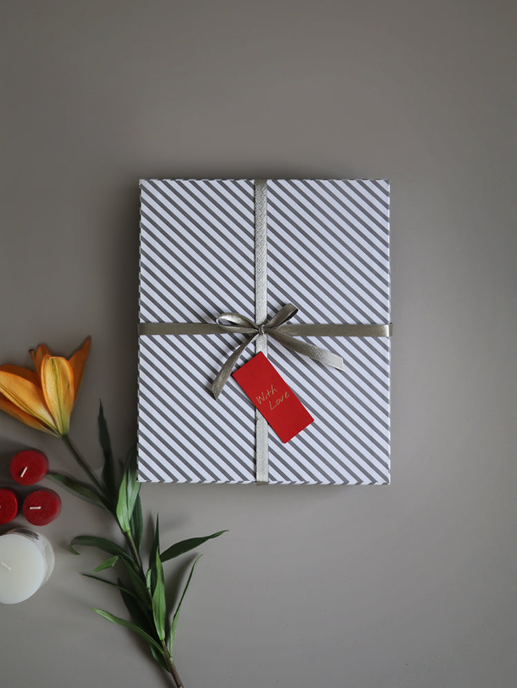 Grey striped gift box tied with ribbon and a red tag